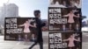 A man walks by a bus stop displayed with posters depicting impeached South Korea's President Park Geun-hye in pink manipulating three of her aides while she is also manipulated as a marionette by her jailed confidante Choi Soon-sil, seen above Park's left shoulder, in Seoul, South Korea, Dec. 27, 2016.