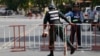 A riot police officer, left, enters a blocked street near the Supreme Court where former party leader Kem Sokha is to appear, in Phnom Penh, Cambodia, Aug. 22, 2018. 