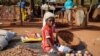 In this Wednesday, May 13, 2020, photo, a child sits on the ground selling onions at a market stall in Tougan, Burkina Faso. 