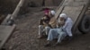 FILE - An elderly Afghan refugee trims his beard while another plays with his grandson on the outskirts of Islamabad, Pakistan. The Afghan government revealed Monday that more than one million refugees have “voluntarily” returned home from Pakistan and Iran in 2016.