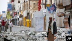 FILE - A Shiite fighter known as a Houthi stands guard in front of buildings destroyed by a Saudi-led airstrike in Sana'a, Sept. 5, 2015. 