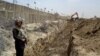FILE - In this May, 16, 2014 file photo, a Pakistani border guard stands alert as an excavator digs a trench along Pakistan Afghanistan border at Chaman post in Pakistan.