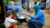 FILE - A Syrian refugee woman with her children prepares food near her tent in a camp for Syrians who fled their country’s civil war, in the Chouf mountain town of Ketermaya, Lebanon. 