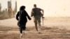 A woman reporter runs with a rebel fighter to avoid snipers at the frontline against the Islamic State fighters in Aleppo's northern countryside, Syria, Oct. 10, 2014.