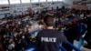 A policeman observes the scene as immigrants who arrived aboard a cargo ship from Turkey queue for meals in a basketball arena where they have been given temporary shelter in the town of Ierapetra, Crete, Nov. 28, 2014. 