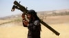 An Islamist Syrian rebel group Jabhat al-Nusra fighter talks on a walkie-talkie while carrying his weapon on Al-Khazan frontline of Khan Sheikhoun, northern Idlib province, Syria, May 17, 2014. 