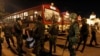 FILE - Thai soldiers stand as anti-government protesters board a bus to head home, at the Royal Plaza in Bangkok.