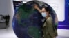 FILE - A visitor to a trade show places her hand on a globe in Beijing, China, Tuesday, Sept. 7, 2021. China and the European Union held talks on topics including artificial intelligence and cross-border data flows on Sept. 18, 2023, in Beijing