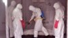 Health workers wearing protective gear spray the shrouded body of a man with disinfectant as they suspect he died from the Ebola virus, at a USAID, American aid Ebola treatment center at Tubmanburg on the outskirts of Monrovia, Liberia, Nov. 28, 2014.