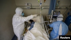 Medical workers in protective suits attend to a patient inside an isolated ward of Wuhan Red Cross Hospital in Wuhan, the epicenter of the novel coronavirus outbreak, in Hubei province, China, Feb. 16, 2020. (Credit: China Daily)