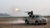 In a picture released May 20, 2015, by the website of Islamist militants, an Islamic State fighter fires his weapon during a battle against Syrian government forces on a road between Homs and Palmyra, Syria. 