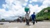 People cross a river with their belongings where a bridge once stood in Phaloni, Malawi, Jan. 22, 2015. 