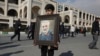 FILE - A boy carries a portrait of Iranian military leader Qassem Soleimani, who was killed in a U.S. airstrike in Iraq, prior to the Friday prayers in Tehran, Iran, Jan. 3, 2020. 