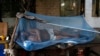 A laborer sleeps on a makeshift bed covered with a mosquito net on a hot summer morning in New Delhi May 23, 2013.