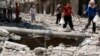 A girl gestures as she walks on the rubble of collapsed buildings at a site hit by what activists said was a barrel bomb dropped by forces loyal to Syria's President Bashar al-Assad in Aleppo's district of al-Sukari, June 17, 2014. 