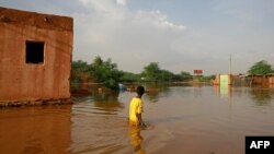 A boy wades through a flooded street in the area of al-Qamayir in the capital's twin city of Omdurman, Sudan, Aug. 26, 2020.