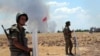 Turkish soldiers stand guard on the Turkish side of the border in Suruc, June 26, 2015, as smoke from nearby fighting rises in the background. 