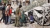 Residents inspect a destroyed Red Crescent ambulance at a site hit by what activists said was a barrel bomb dropped by forces loyal to Syria's President Bashar al-Assad, in al-Haidariya neighborhood, Aleppo, Oct. 2, 2014. 