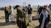 FILE - An Afghan plaincloth security personnel, holds his weapon as he walks among Pakistani refugees, at Gulan camp, some 20 kilometers (12 miles) from the border in the restive Khost province, Afghanistan, Jan. 19, 2015.