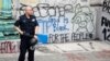 Un agente de la policía de Nueva York protege una de las zonas vandalizadas por los manifestantes que solicitan un recorte al presupuesto de la policía de la ciudad.