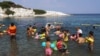 Des enfants réfugiés et migrants apprennent à nager sur la mer près du camp de réfugiés de Kara Tepe à Mytilène, sur l'île de Lesbos, le 10 août 2016.