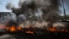 People walk through a square as black smoke billows from burning tires to prevent government armored personnel carriers from passing through the center of Mariupol, eastern Ukraine, May 10, 2014. 
