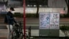A man wearing a mask looks at his smartphone next to a poster celebrating the Tokyo 2020 Olympics Tuesday, March 3, 2020, in Tokyo. The Japanese government has indicated it sees the next couple of weeks as crucial to containing the spread of COVID…