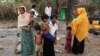 FILE - A family stands beside remains of a market which was set on fire, in Rohingya village outside Maungdaw, in Rakhine state, Myanmar. 