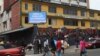 Pedestrians walk past a sign reading "Ebola disease outbreak" outside the Ministry of Finance in Monrovia, Liberia, Jan. 12, 2015.