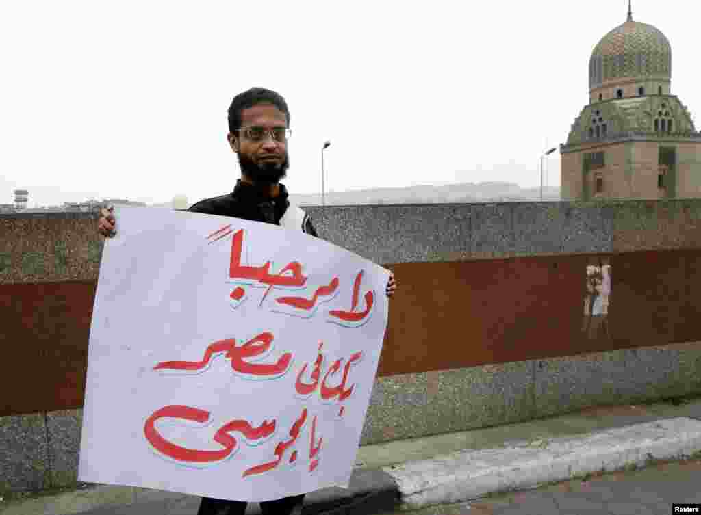 A man holds a sign in Arabic reading, "(Ahmedinejad) You are not welcome in Egypt", in front of the al-Azhar mosque during Ahmedinejad's visit in Cairo, February 5, 2013.