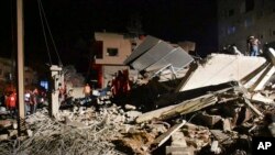 Anggota pasukan keamanan Suriah dan pasukan pertahanan sipil berkumpul di gedung yang hancur oleh serangan Israel di Homs, Suriah, pada 6 Februari 2024. (Foto: SANA via AP)
