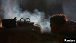 A woman uses firewood to cook food in her home, in Sapay, Nepal, about 900 kilometers from Kathmandu, Feb. 17, 2014.