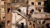 A Lebanese flag hangs in front of the buildings that were damaged by an explosion at the Beirut port, in the neighborhood of Karantina, Lebanon, Aug. 13, 2020. 