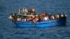 Migrants sit in their boat during a rescue operation by Italian navy ship Grecale (not pictured) off the coast of Sicily, in this handout picture by the Italian Marina Militare, June 29, 2014.
