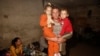 FILE - A local resident holds his children in a basement which is being used as a shelter following shelling in Donetsk, eastern Ukraine.