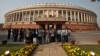 FILE - People stand in front of the Indian parliament building on the opening day of the winter session in New Delhi, Nov. 22, 2012. 