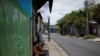 FILE - Residents wait outside a house and near a white flag as a sign to ask for food, in a low-income neighborhood during the coronavirus outbreak, in San Salvador, El Salvador, May 14, 2020.