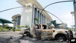 FILE - Burnt-out cars are seen outside a government building, following an election protest in Libreville, Gabon, Sept. 1, 2016.