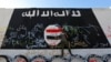 FILE - A member of militias known as Hashid Shaabi stands next to a wall painted with the black flag commonly used by Islamic State militants, in the town of al-Alam, Iraq.