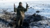 FILE - A Ukrainian soldier shows pieces of shrapnel in a crater left by an explosion in Avdiivka, Ukraine, Jan. 31, 2017.