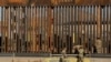 Los soldados estadounidenses caminan junto a la cerca fronteriza entre México y Estados Unidos, mientras se observa a los migrantes caminando detrás de la cerca, luego de cruzar ilegalmente a EE.UU. para entregarse en El Paso, Texas.