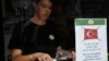 FILE - An employee stands behind a sign depicting a crossed out Turkish flag taped to the window of a coffee shop in Tel Aviv, Oct. 27, 2009. 
