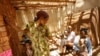 FILE - Malagasy women and children wait in the shade at a makeshift village clinic in Antanetikely, Madagascar, Oct. 23, 2007.