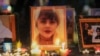 FILE - Candles and pictures of Mahsa Amini, who died in custody of Iran's morality police, are shown during a vigil for Amini, in Los Angeles, Sept. 29, 2022. 