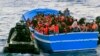 In this photo released by the Italian Navy on May 22, 2014, a fishing boat filled with migrants receives aid from an Italian Navy motor boat. 