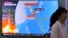 A woman passes by a TV screen showing a local news program reporting on North Korea's threats to strike Guam with missiles, at the Seoul Train Station in Seoul, South Korea, Aug. 10, 2017. 