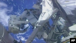 A frame from NASA TV, NASA shows astronaut Ricky Arnold, left, and NASA astronaut Drew Feustel shuffling around a couple of space station pumps at the International Space Station on May 16, 2018.