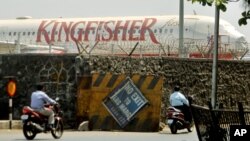 Commuters drive past a stationary aircraft belonging to Kingfisher airlines at the domestic airport in Mumbai, India, March 20, 2012.