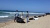 FILE - Public service workers bag bodies of migrants who drowned off Tripoli's coast, Aug. 25, 2014. 