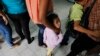 FILE - Women and their children wait in line to register at the Honduran Center for Returned Migrants.